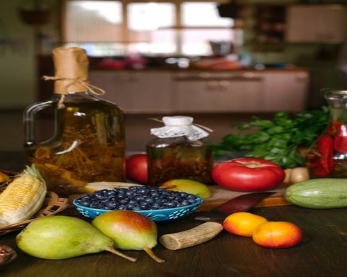 Fresh vegetables and olive oil on a wooden kitchen table